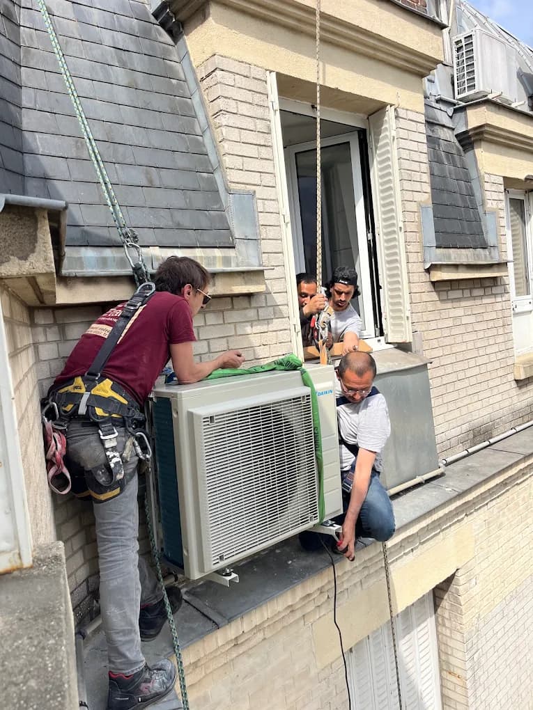 Technicians installing an air-conditioning outdoor unit at height on a building façade