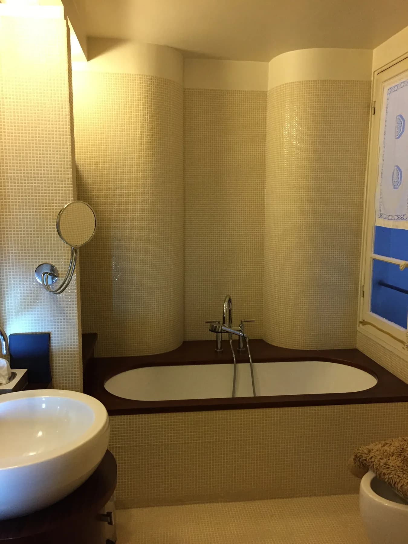 Built-in bathtub surrounded by beige mosaic tiling