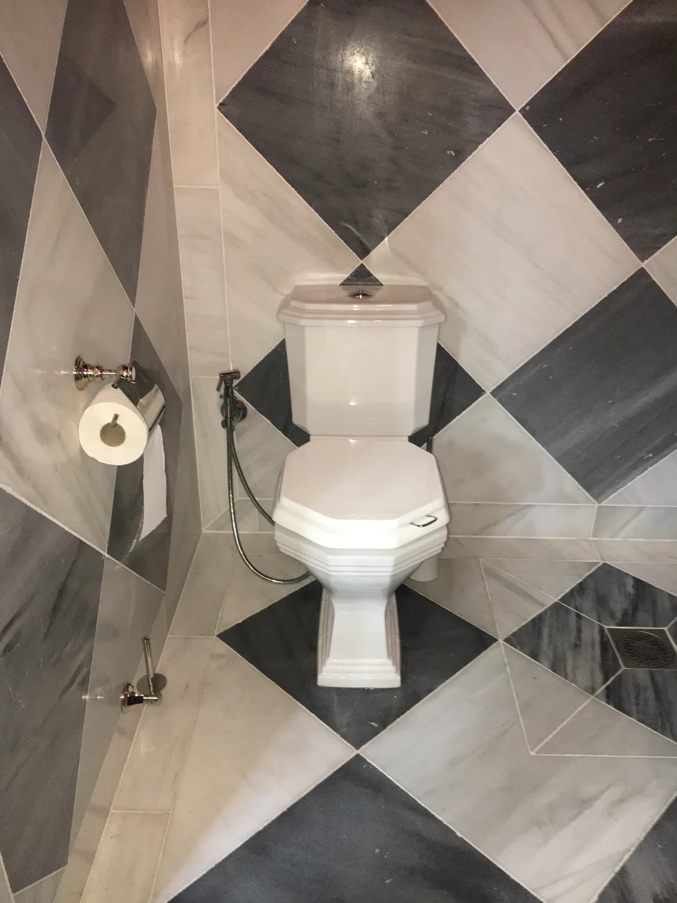 WC in a room with black-and-white marble tiling